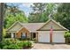 Charming one-story brick home featuring an attached two-car garage and lush, mature landscaping at 2080 Bankston Cir, Snellville, GA 30078