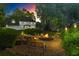 Twilight view of a backyard with a fire pit, outdoor lighting, and mature trees creating a serene ambiance at 4365 Wicklow Ct, Suwanee, GA 30024