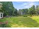 Large grassy backyard with mature trees, manicured hedges, and an outdoor seating area at 4365 Wicklow Ct, Suwanee, GA 30024