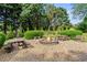 Backyard fire pit surrounded by gravel, wooden benches, and lush landscaping for outdoor entertaining at 4365 Wicklow Ct, Suwanee, GA 30024