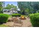 Backyard fire pit with outdoor seating, surrounded by manicured landscaping and mature trees at 4365 Wicklow Ct, Suwanee, GA 30024