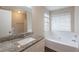 Bright bathroom featuring a granite vanity and soaking tub with tiled surround at 6590 Smoke Ridge Dr, Atlanta, GA 30349