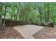 View of the backyard featuring a basketball court and fence with mature trees surrounding the property at 6700 Knollwood Cir, Douglasville, GA 30135