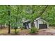 View of the exterior featuring a driveway and garage with mature trees surrounding the property at 6700 Knollwood Cir, Douglasville, GA 30135