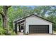 View of garage with black trim and white siding; surrounded by lush, mature trees at 6700 Knollwood Cir, Douglasville, GA 30135