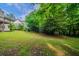 Grassy backyard with mature trees and a partial view of the home's exterior at 5310 Arrowind Nw Rd, Lilburn, GA 30047