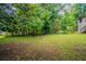 Lush backyard with green grass and trees; partial house view with stairs at 5310 Arrowind Nw Rd, Lilburn, GA 30047