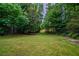 Expansive, green backyard surrounded by mature trees and partial fencing at 5310 Arrowind Nw Rd, Lilburn, GA 30047