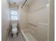 Bright bathroom with a shower-tub combo and a toilet under a window at 5310 Arrowind Nw Rd, Lilburn, GA 30047