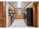 Well-lit kitchen with black appliances, tiled flooring, and light wood cabinetry at 5310 Arrowind Nw Rd, Lilburn, GA 30047