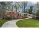 Charming red brick home featuring black shutters, mature trees, and a winding driveway at 1415 Dalewood Ne Dr, Atlanta, GA 30329
