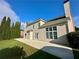 A two-story beige house boasts a chimney, large windows, and a concrete patio surrounded by a green lawn at 1805 Hunters Moon Dr, Alpharetta, GA 30005