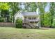 Charming home with a wooden porch and stairs, surrounded by lush greenery and a picket fence at 3021 Mills Ridge Dr, Canton, GA 30114