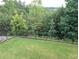A well-maintained backyard featuring lush green grass and an iron fence, offering privacy and a beautiful view of the surrounding trees at 322 Woodridge Pass, Canton, GA 30114