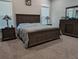 Cozy main bedroom featuring carpeted floors, a large bed with a wooden frame, and a matching dresser at 322 Woodridge Pass, Canton, GA 30114