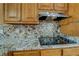 Close-up of kitchen with granite counters, tile backsplash, and stainless steel vent hood at 1103 Wallington Nw Ct, Conyers, GA 30012