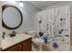 Charming bathroom with a floral shower curtain, wood vanity, and an elegant round mirror at 262 Sandhurst Ct, Suwanee, GA 30024