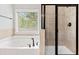 Bright bathroom with a large soaking tub, tiled walls, and a black framed glass enclosed shower at 2887 Regal Park Ct, Duluth, GA 30096
