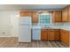 Well-lit kitchen with white appliances, wood cabinets, and updated vinyl flooring at 2045 Scarbrough Dr, Stone Mountain, GA 30088