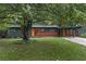Charming single-story home featuring a well-manicured lawn and mature trees with a brick accent and cheerful orange front door at 3580 Raymond Dr, Atlanta, GA 30340