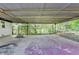Covered outdoor patio featuring a chain-link fence and access to a spacious, tree-lined backyard at 3991 Adamsville Sw Dr, Atlanta, GA 30331