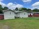The rear of the house shows a covered porch and a lawnmower by a red fence at 60 King Blvd, Mcdonough, GA 30253