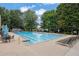 Large community swimming pool with lounge chairs, tables, and umbrellas, perfect for relaxation and recreation on sunny days at 1925 Stonewyck Ct, Cumming, GA 30041