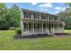 Inviting two-story home with a spacious front porch, American flag, gray siding, and well-manicured landscaping at 1925 Stonewyck Ct, Cumming, GA 30041