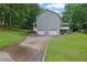 A gray two-story home features a two-car garage and a concrete driveway surrounded by mature trees and a well-maintained lawn at 1925 Stonewyck Ct, Cumming, GA 30041