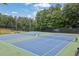 Well-maintained community tennis courts with green and blue surfaces, surrounded by lush trees and marked with clear signage at 1925 Stonewyck Ct, Cumming, GA 30041