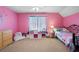 Whimsical bedroom painted in shades of pink has a iron bed and play and storage areas at 3519 Wellsley Dr, Powder Springs, GA 30127