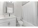 Modern bathroom with white vanity, sleek black faucet, toilet, and bathtub with white shower curtain at 410 Ward Farm Dr, Powder Springs, GA 30127