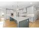 Modern kitchen with stainless steel appliances, large island with seating, stylish pendant lights, and hardwood floors at 410 Ward Farm Dr, Powder Springs, GA 30127