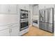 Modern kitchen with stainless steel appliances, double oven, white cabinets, and beautiful hardwood floors at 410 Ward Farm Dr, Powder Springs, GA 30127