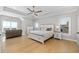Spacious primary bedroom with tray ceiling, windows, light hardwood floors, and stylish furniture at 410 Ward Farm Dr, Powder Springs, GA 30127