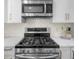 A stainless steel gas cooktop and microwave against a white backsplash in a modern kitchen at 270 Park Bridge Ln, Roswell, GA 30075