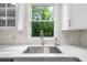 A kitchen sink with white quartz countertops and a view to a lush wooded yard at 270 Park Bridge Ln, Roswell, GA 30075