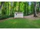 Backyard view of a well-maintained storage shed surrounded by lush greenery and trees at 270 Park Bridge Ln, Roswell, GA 30075