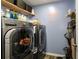 Modern laundry room with front load washer and dryer, wood look floors and storage shelf at 510 Curry Ridge Ct, Locust Grove, GA 30248