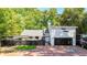Contemporary home featuring a two-car garage, black privacy fence, brick driveway and mature landscaping at 1048 Indian Hills Pkwy, Marietta, GA 30068