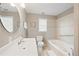 Bright bathroom featuring a soaking tub, white vanity with a round mirror, and neutral wall colors at 4108 Wyndam Hill Dr, Suwanee, GA 30024