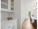 Wet bar beside the dining area that features marble countertops, white cabinets, white subway tile and dark wood floors at 4108 Wyndam Hill Dr, Suwanee, GA 30024
