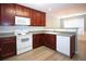 Functional kitchen with white appliances, cherry cabinets, laminate countertops and hardwood floors at 942 Village View Cir, Loganville, GA 30052