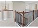 Carpeted hallway featuring a dark wood railing and chandelier, connecting to the upper level of the home at 29 Lankford Rd, Tucker, GA 30084