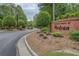 Community entrance sign amidst lush greenery and brick pillars, leading to a paved road at 95 Weslyan Way, Oxford, GA 30054