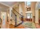 Elegant foyer with hardwood floors, staircase, chandelier, and decorative front door, creating a grand entrance at 95 Weslyan Way, Oxford, GA 30054