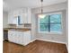 Cozy eat-in kitchen featuring a window with backyard views, white cabinets, and laminate wood flooring at 2786 Olde Gate Ct, Snellville, GA 30078