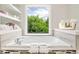 A relaxing tub sits beneath a window with a view, accented by mosaic tile and decorative shelving at 667 Creswell Park, Smyrna, GA 30082