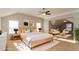 Staged bedroom with king bed, sitting area, ceiling fan, ensuite bathroom, and sunny windows at 122 Melrose Creek Dr, Stockbridge, GA 30281