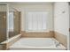 Well-lit bathroom featuring a soaking tub and a separate glass-enclosed shower for spa-like experience at 251 Sumac Trl, Woodstock, GA 30188